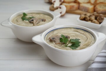 Delicious mushroom cream soup with parsley on white wooden table