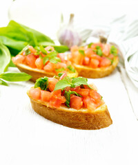 Bruschetta with tomato and spinach on light board