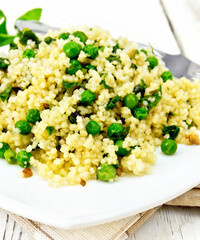 Couscous with spinach and green peas in dish on towel