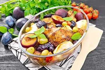 Chicken with fruits and tomatoes in glass pan on table
