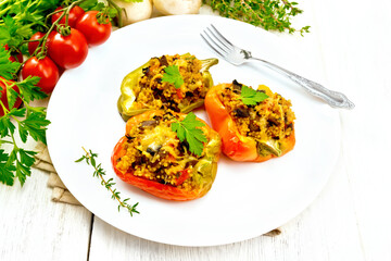 Pepper stuffed with mushrooms and couscous in white plate on light board
