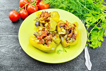 Pepper stuffed with vegetables in green plate on dark board