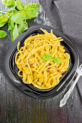 Spaghetti with pumpkin and bacon in plate on black board top