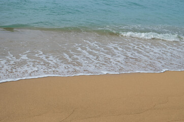 Fototapeta na wymiar Waves and Foam on a Sand Beach