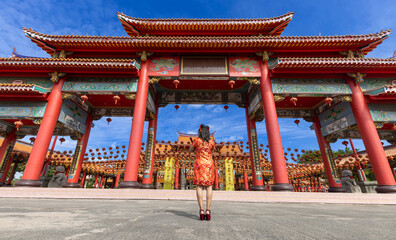 Rear view of Asian woman in red cheongsam qipao dress is visiting the Chinese Buddhist temple during lunar new year for traditional culture concept the Chinese word means blessing for all