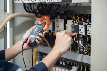 Electrician engineer work tester measuring voltage and current of power electric line in electical cabinet control , concept check the operation of the electrical system . - obrazy, fototapety, plakaty