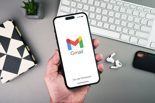 Man holding a smartphone with Google Gmail app on the screen on grey background table. Office environment. Rio de Janeiro, RJ, Brazil. January 2023