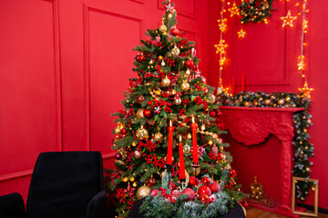 Three burning red candles against the background of a Christmas tree bokeh, lights and decorations. Concept of christmas and new year.