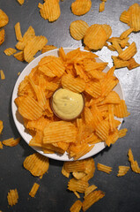 potato chips with cheese sauce on a white plate on a black and gray loft background