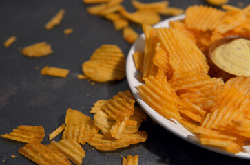 potato chips with cheese sauce on a white plate on a black and gray loft background