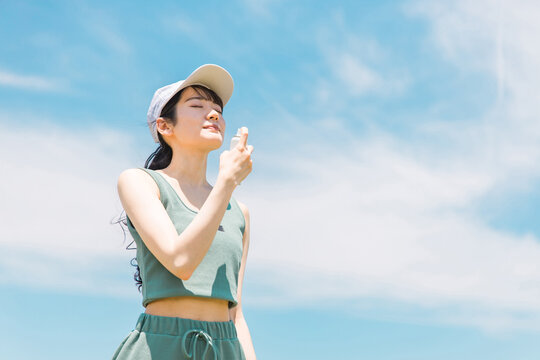 夏の運動前に制汗スプレー・UVケア・デオドラントケアをする日本人女性
