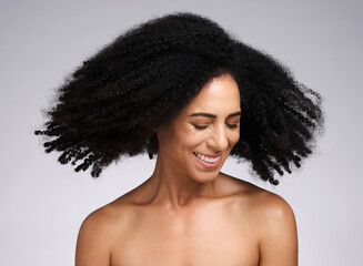 Beauty, black woman and afro shake for hair care campaign with playful smile and natural texture. Happiness, wellness and hair volume of african model with healthy skincare in white studio.