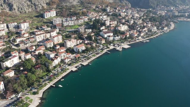 Kotor Montenegro waterfront - Roofs on houses and buildings along the coastline, in residential neighborhood of Dobrota, between rocky hills and Mediterranean sea bay. Aerial drone view.