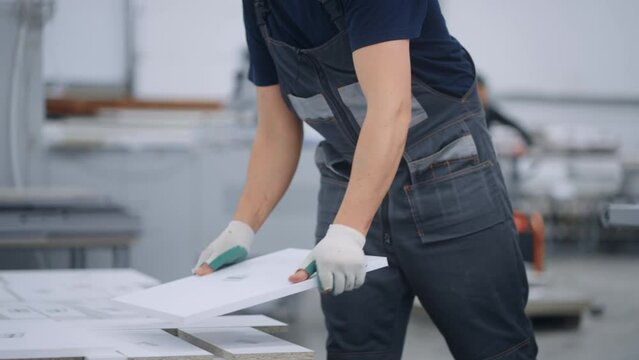 human labor in furniture manufacturing factory, worker man taking chipboard details from machine