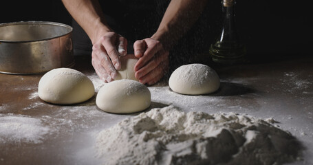 Bakery worker forming loafs of organic bread. Cooker making dough with natural ingredients. Hands covered in flour close up 