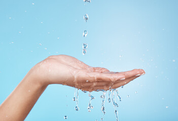 Hand, water and hydration with a woman cleaning in studio on a blue background for hygiene or...