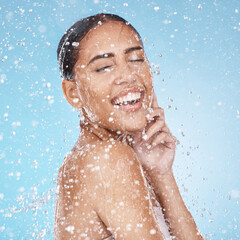 Laughing woman, face skincare or water splash on blue background studio in healthcare wellness,...
