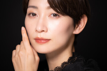 お肌を気にする女性　黒バック　カメラ目線