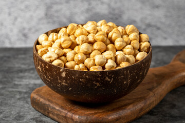 Roasted hazelnut nuts on dark background. Fresh hazelnuts in a coconut bowl. Studio shoot. close up