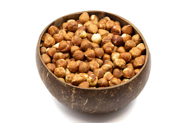 Roasted hazelnuts isolated on white background. Nuts in a coconut bowl. Studio shoot. close up