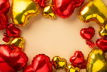 Valentine's Day decorations concept. Top view photo of heart shaped red and yellow balloons on isolated pastel beige background with copyspace in the middle