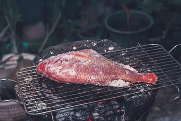 The ruby fish is coated with salt and placed on a charcoal grill in a clay oven.