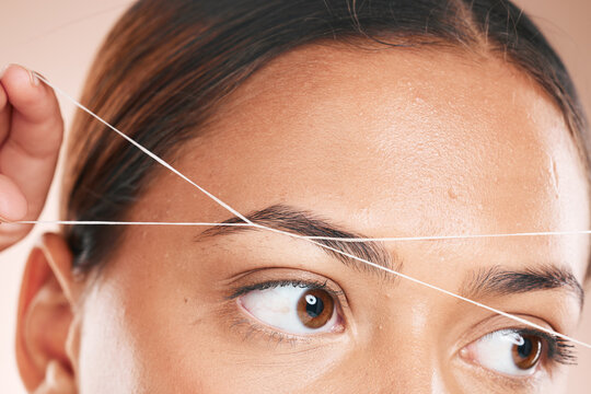 Threading, eyebrows and beauty with a model black woman in studio on a beige background for hair removal. Eyes, zoom and wellness with an attractive young female using a product on her face
