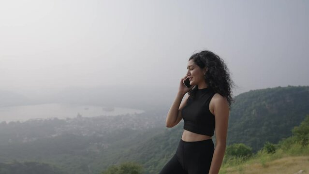 young Indian  girl doing  call with by friend.Talking to Mobile call. young Asian  Beautiful smiling woman pretty face alone at the top of mountain using mobile phone.
