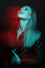 Fashion and make-up concept. Beautiful woman with checkered black suit studio portrait in red and blue color split effect. Futuristic looking style. Model looking up with excitement in her face