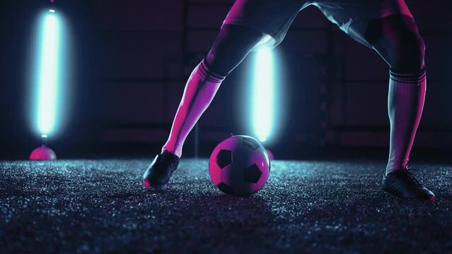 high skilled professional football player training in night, closeup of feet with ball, dribbling