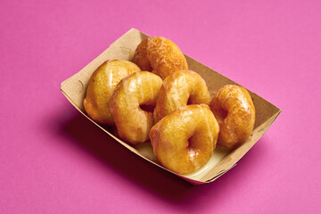 Fresh donuts with sweet sauce on a pink background.