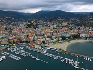 Aerial view of Sanremo, Italian city on the seashore in Liguria, north Italy. Drone flying along the port over beaches and boardwalk with palm trees and Birds Eye of yacht parking in San Remo, Italy.