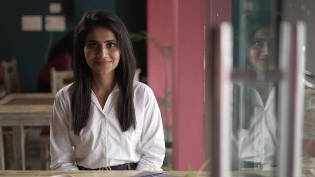 Young woman Asian smiling and looking at camera. Portrait of a happy beautiful young Indian  woman in the cafe. Close up face of young cool trendy woman looking at camera.