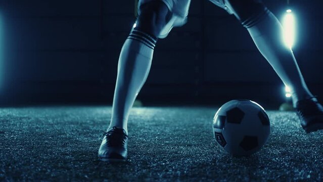 football player practicing dribbling and dummy by feet and ball on field, closeup view