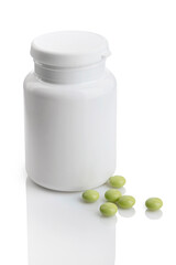 Green pills scattered around a medicines bottle