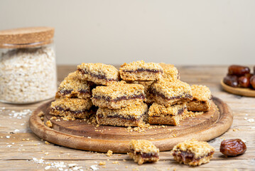 Homemade old fashioned date squares or Matrimonial bars on round wooden cutting board with ingredients