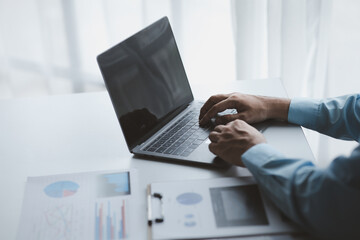 A business man is checking company financial documents and using a laptop to talk to the chief financial officer through a messaging program. Concept of company financial management.