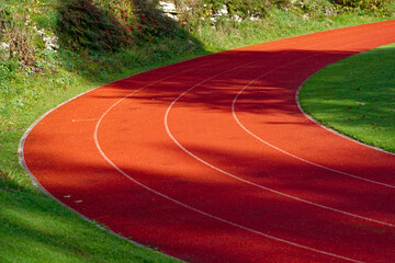 Curve of red tartan track with four lanes at village of Magglingen on a sunny autumn day. Photo taken November 10th, 2022, Magglingen Macolin, Switzerland.
