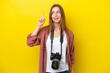 Young photographer caucasian woman isolated on yellow background intending to realizes the solution while lifting a finger up