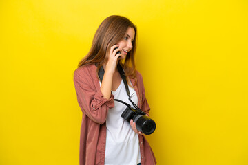 Young photographer caucasian woman isolated on yellow background keeping a conversation with the...