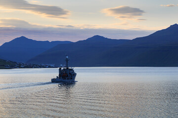 Coast Guard patrol boat in a fjord with a rocky shore in the background at night