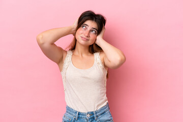 Young caucasian woman isolated on pink background frustrated and covering ears