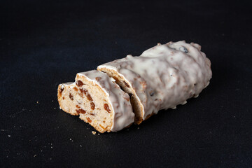 Slices of fruit bread in white glaze on a dark background, dessert