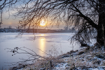 Krajobraz zimowy. Widok ze wschodem słońca i zimowy poranek nad rzeką. Zamrożona rzeka. Świtanie w zimowej scenerii. Mroźny poranek. Tło natury.	 - obrazy, fototapety, plakaty