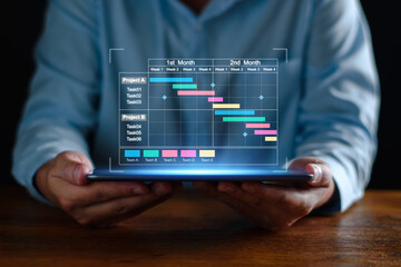 Project manager working on tablet and updating tasks and milestones progress planning with Gantt chart scheduling interface for company on virtual screen. Business Project Management System.