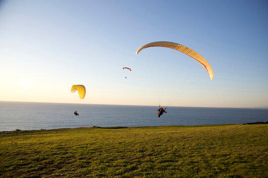 Paraglider takes off as two other paragliders ride by from the paragliding port in Torrey Pines, San Diego, California.