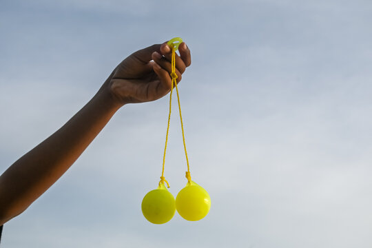 Lato-lato is a type of traditional game that can be found in Indonesia. lato-lato being held by a boy against a sky background.