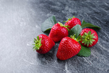 Reife rote Erdbeeren aus biologischem Anbau angeboten als close-up auf einem grauen Board mit...