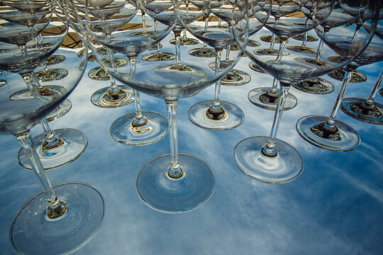 Wine glasses on a glass table with the reflection of the sky