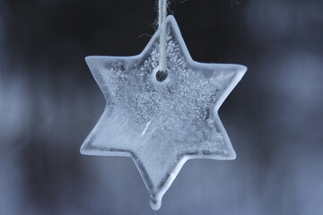 A star shaped ice ornament hanging from the tree.
